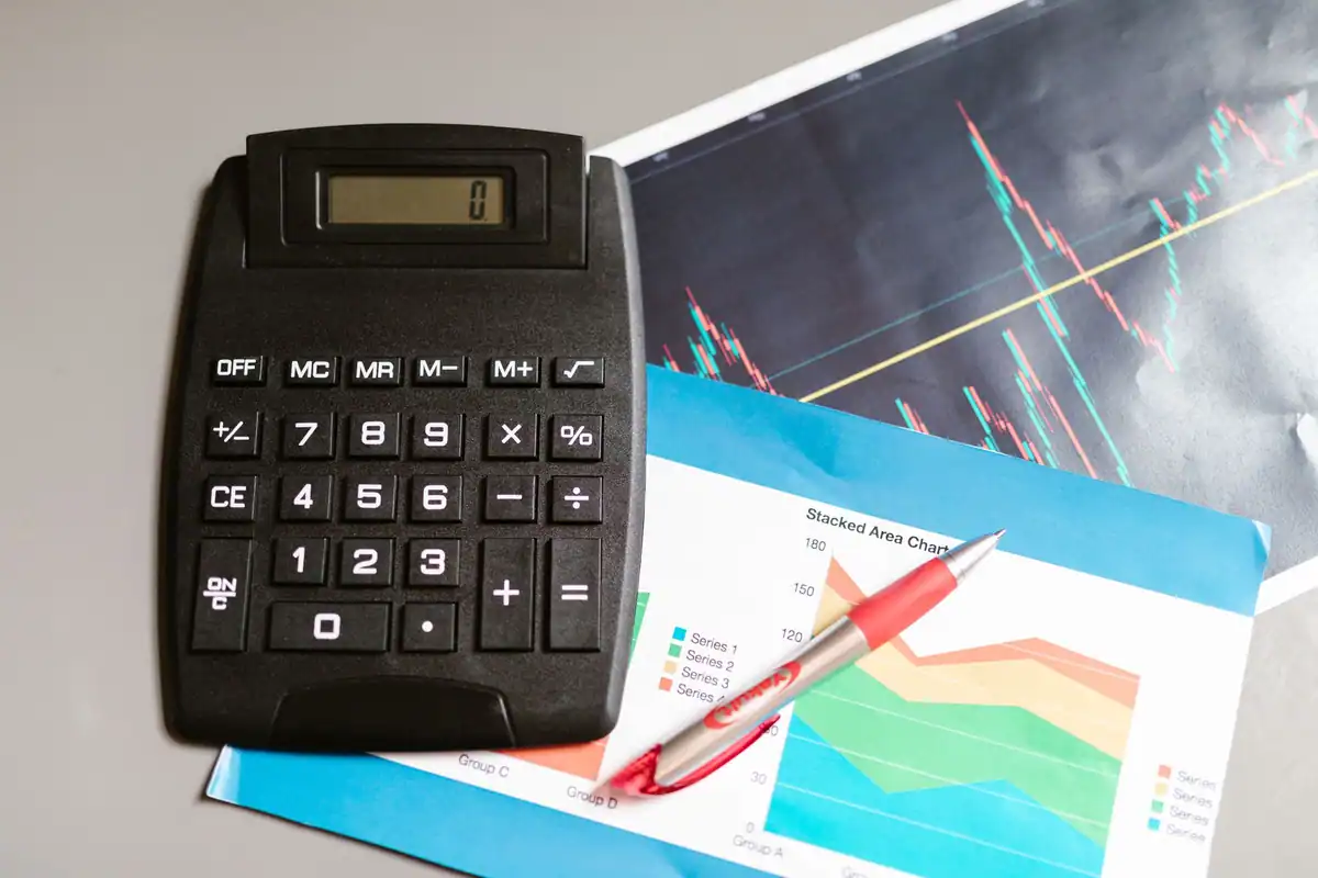 Calculator, creion roșu și foi cu grafice colorate așezate pe un birou