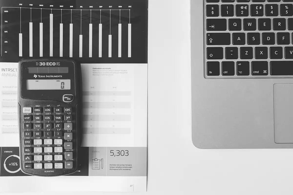 Calculator, tastatură de laptop și foi cu cifre pe o suprafață albă