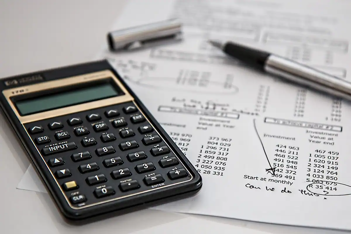 Calculator financiar așezat pe foi cu tabele și un pix elegant